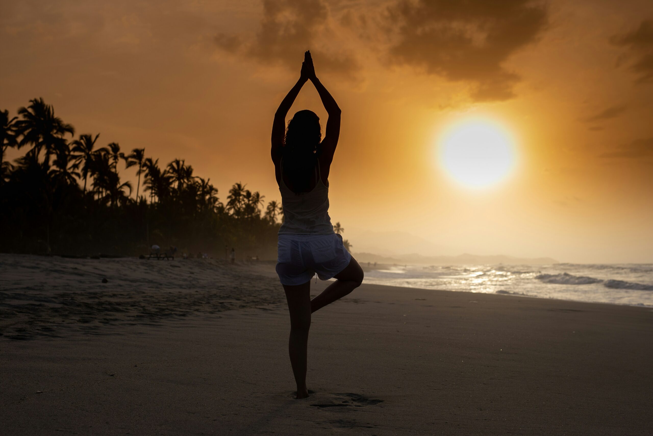 person doing yoga on beach at sunset